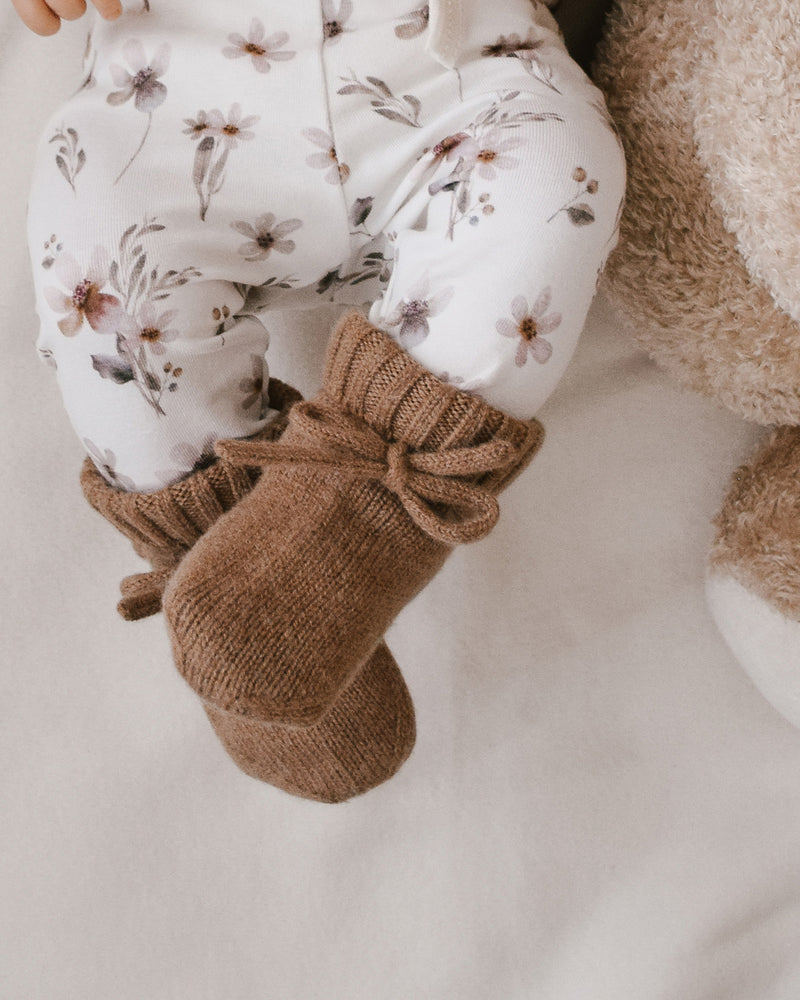 baby in handgemaakte babykleding met newbornbroekje van organisch katoen en bruine wollen slofjes.